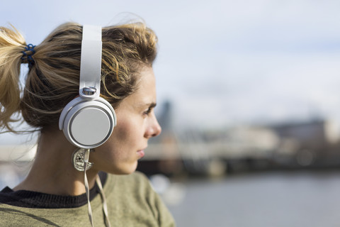 UK, London, Frau hört Musik an der Themse, lizenzfreies Stockfoto