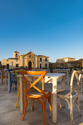 Sizilien, Marzamemi, Tische und Stühle eines Restaurants, Kapelle im Hintergrund - CSTF001017