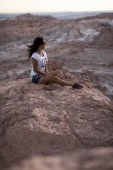 Chile, San Pedro de Atacama, Frau sitzt auf einem Felsen in der Atacama-Wüste - MAUF000343