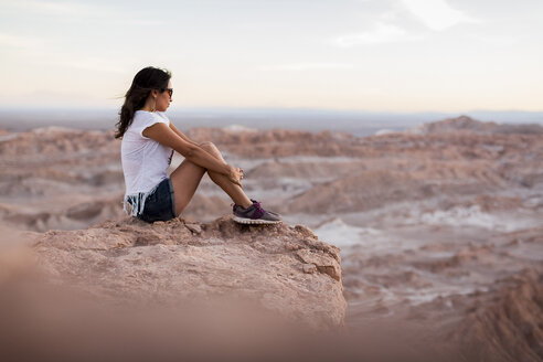 Chile, San Pedro de Atacama, Frau sitzt auf einem Felsen in der Atacama-Wüste - MAUF000346