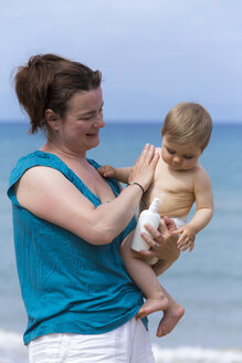 Mutter cremt ihr Baby am Strand mit Sonnencreme ein - DSF000642