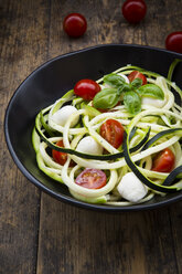 Schüssel mit Zucchini-Spaghetti mit Mozzarella, Kirschtomaten und Basilikum auf Holz - LVF004637