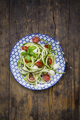 Schüssel mit Zucchini-Spaghetti mit Mozzarella, Kirschtomaten und Basilikum auf Holz - LVF004640