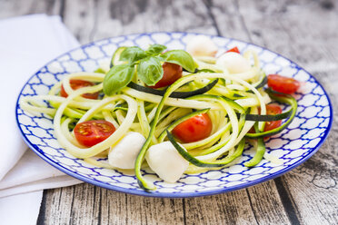 Schüssel mit Zucchini-Spaghetti mit Mozzarella, Kirschtomaten und Basilikum auf Holz - LVF004642