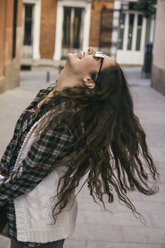 Laughing young woman with long brown hair wearing sunglasses - ABZF000285
