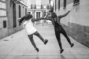 Spanien, Madrid, Rückenansicht von zwei jungen Frauen, die auf einer Straße springen - ABZF000287