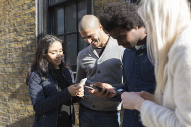 Group of happy friends looking at cell phones - BOYF000176