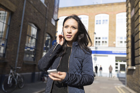 Junge Frau mit Mobiltelefon auf einer städtischen Straße - BOYF000178