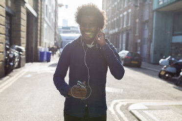 Young man listening to music from cell phone on urban street - BOYF000189