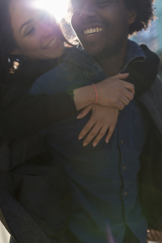 Glücklicher junger Mann trägt Freundin huckepack, lizenzfreies Stockfoto