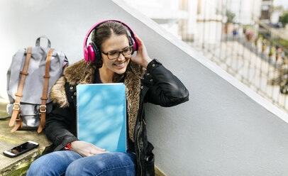 London, student girl with headphone and writing pad, language holiday - MGOF001523