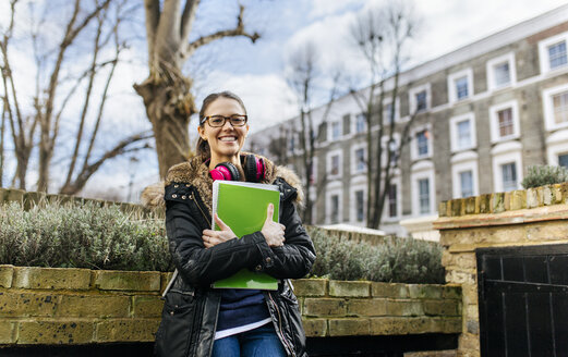 London, student girl with headphone and writing pad, language holiday - MGOF001524