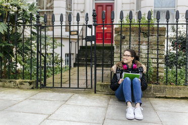 London, Studentin mit Kopfhörer und Schreibblock - MGOF001525