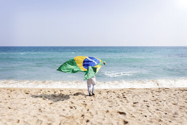 Kleiner Junge läuft mit brasilianischer Flagge am Strand - VABF000364