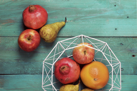 Obstkorb mit Birne, Grapefruit, Granatapfel und Apfel auf Holz, lizenzfreies Stockfoto