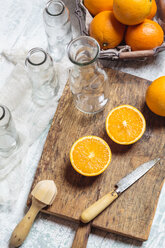 Leere Glasflaschen und geschnittene Orangen auf einem Holzbrett - SBDF002783