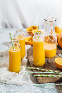 Aufgeschnittene Orangen und Glasflaschen mit frisch gepresstem Orangensaft - SBDF002784