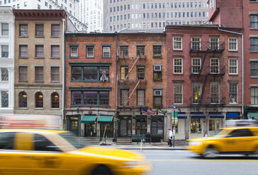 USA, New York City, Manhattan, yellow cabs driving in front of old brick houses - HSI000417