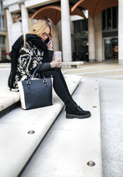 Young woman with handbag on cell phone on stairs - MGOF001532
