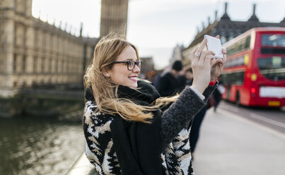 UK, London, young woman taking a selfie on Westminster Bridge - MGOF001544