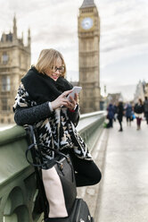 UK, London, junge Frau benutzt ihr Smartphone auf der Westminster Bridge - MGOF001545