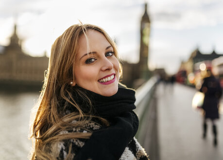 UK, London, Porträt einer lächelnden jungen Frau auf der Westminster Bridge - MGOF001550