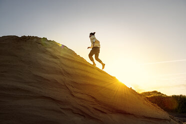 Man with bun running uphill - BMAF000098