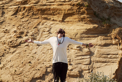 Man with arms outstretched in front of rock - BMAF000100