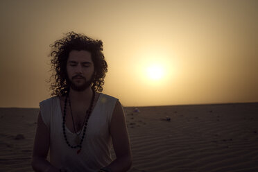 Mann meditiert in der Wüste mit geschlossenen Augen - BMAF000129