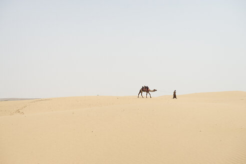 Man leading camel through desert - BMA000136