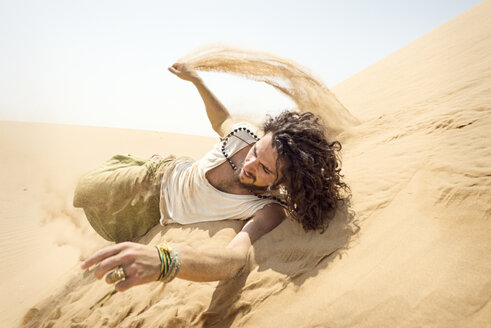 Man rolling down sand dune - BMAF000137