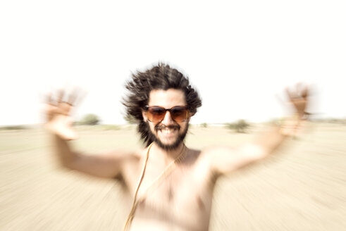 Mann mit nacktem Oberkörper und Sonnenbrille streckt sich in der Wüste aus - BMAF000147