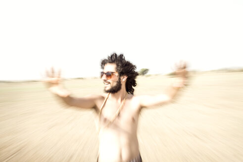 Mann mit nacktem Oberkörper und Sonnenbrille streckt sich in der Wüste aus - BMAF000148