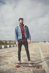 Spain, A Coruna, portrait of young man standing on his longboard - RAEF000945