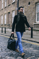 Junger lässiger Geschäftsmann, der auf der Straße geht und eine Tasche trägt - BOYF000215