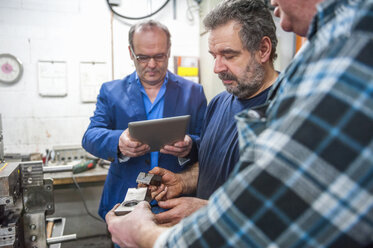 Three men with digital tablet examining workpieces - DIGF000047