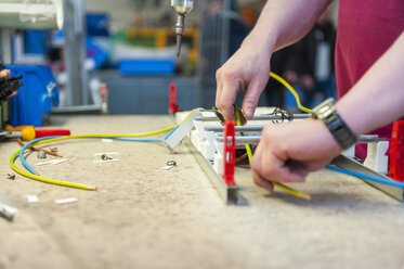 Worker cutting wires on workbench - DIGF000053