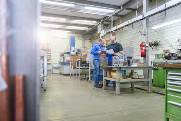 Zwei Männer in einer Fabrik sprechen über ein Metallwerkstück - DIGF000070