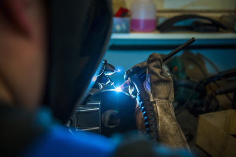 Schweißer bei der Arbeit mit Schutzmaske, lizenzfreies Stockfoto