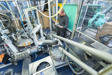 Mann in einer Fabrik bei der Arbeit an einer Sortiermaschine - DIGF000082