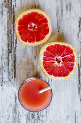 Sliced grapefruit and glass of grapefruit juice on wood - SARF002652
