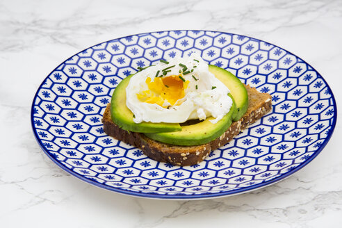 Vollkornbrotscheiben mit geschnittener Avocado und pochierten Eiern auf dem Teller - LVF004671