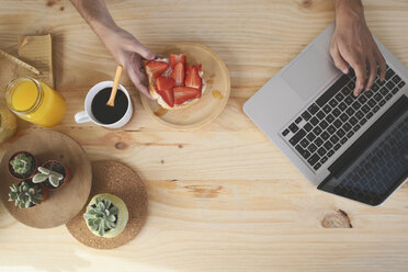 Young man using laptop while having breakfast - RTBF000013