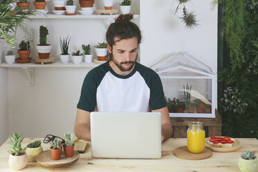 Junger Mann mit Laptop beim Frühstück - RTBF000014