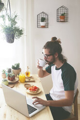 Junger Mann mit Laptop beim Frühstück - RTBF000017