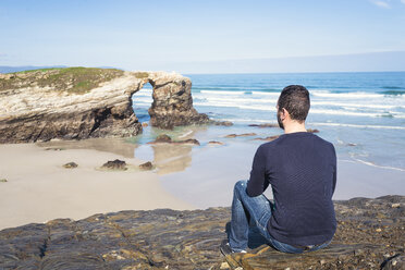 Spanien, Ribadeo, Rückenansicht eines Mannes, der auf den Felsen der Playa de Las Catedrales sitzt - EPF000034