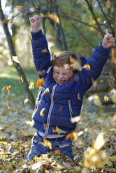 Boy throwing autumn leaves in forest - LBF001417