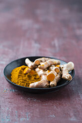 Fresh Curcuma and powder in bowl on wood - MYF001431