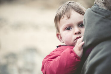 Porträt eines kleinen Jungen, der hinter dem Rücken seiner Mutter späht - RAEF000949