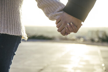 Young couple holding hands at backlight, close-up - ABZF000293